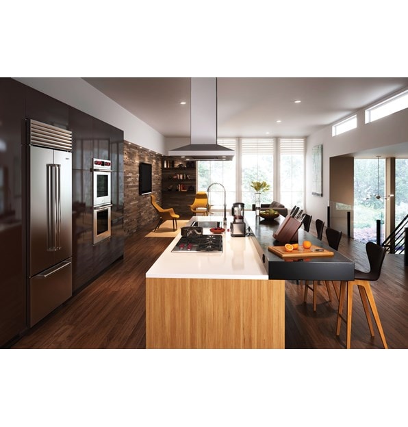 Campana extractora de placa de cocción para isla de 42" Wolf - Inoxidable (VI42S) exhibida centrada sobre una gran isla de cocina de doble nivel frente a la pared de los electrodomésticos Wolf