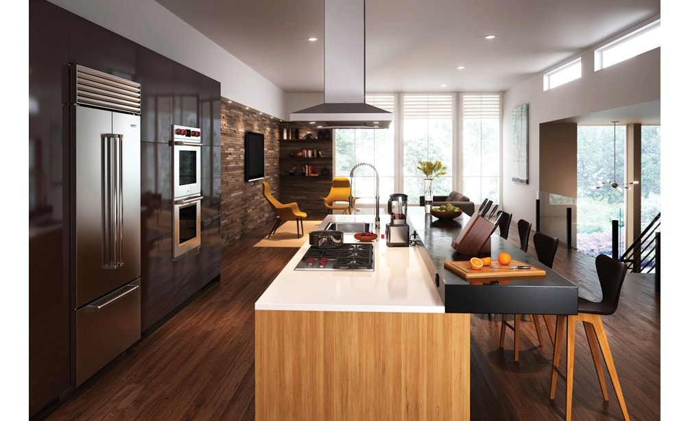 Campana extractora de placa de cocción para isla de 42" Wolf - Inoxidable (VI42S) exhibida centrada sobre una gran isla de cocina de doble nivel frente a la pared de los electrodomésticos Wolf