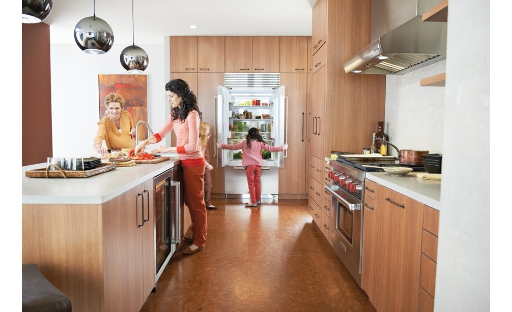 La campana extractora de pared de perfil bajo de 36" Wolf (PW362210) exhibida en una superficie de cocción iluminada en una gran cocina familiar estilo galera