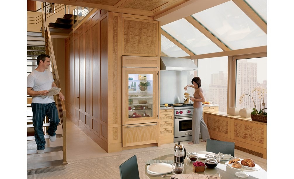 Campana extractora de pared de perfil bajo de 30" Wolf (PW302210) con un diseño de cocina personalizado con techos altos, grandes ventanas y gabinetes de madera natural