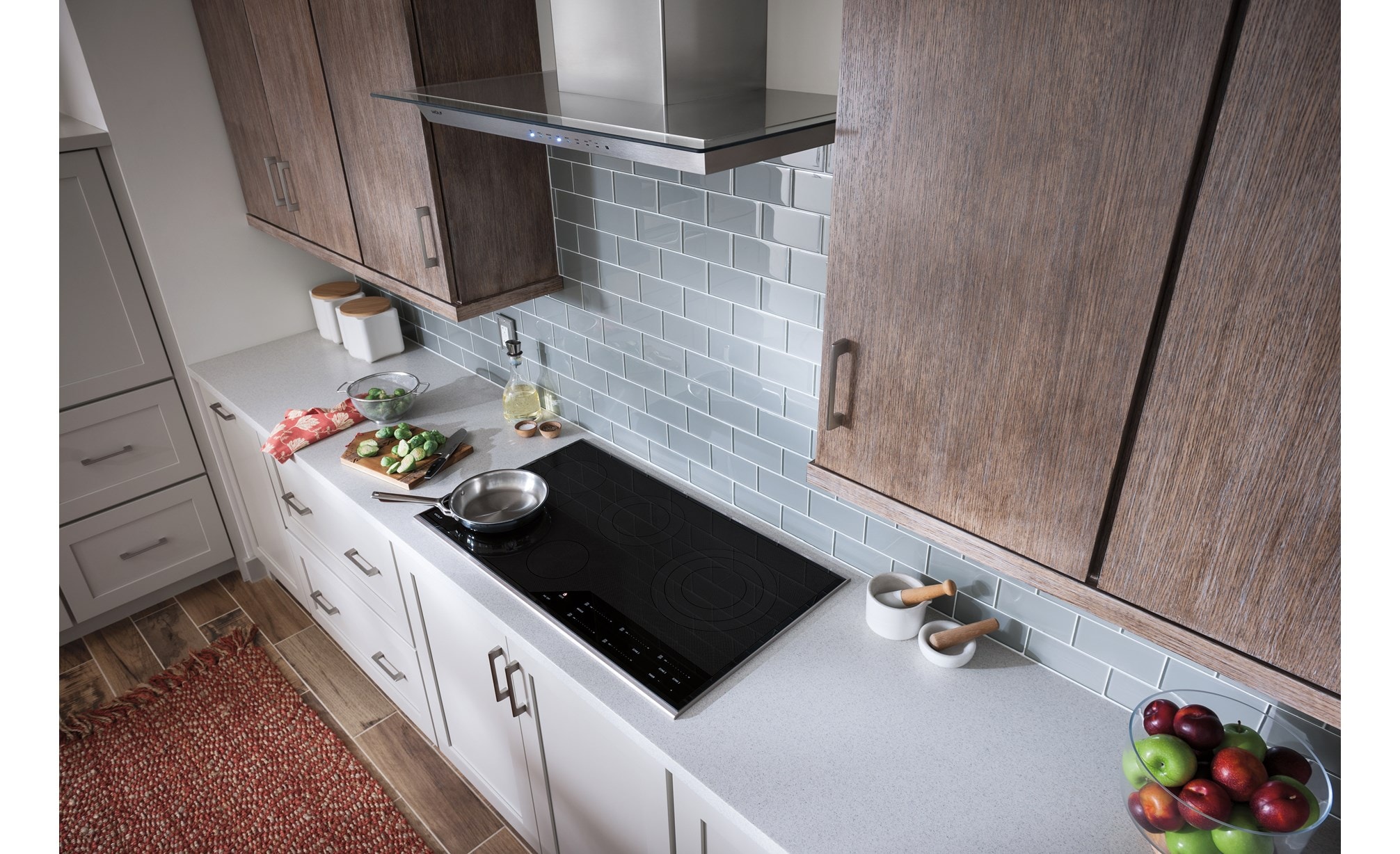 La campana extractora de pared de 36" Wolf de vidrio (VW36G) exhibida en un diseño de cocina acogedor con gabinetes de madera cálida y salpicadero de azulejos