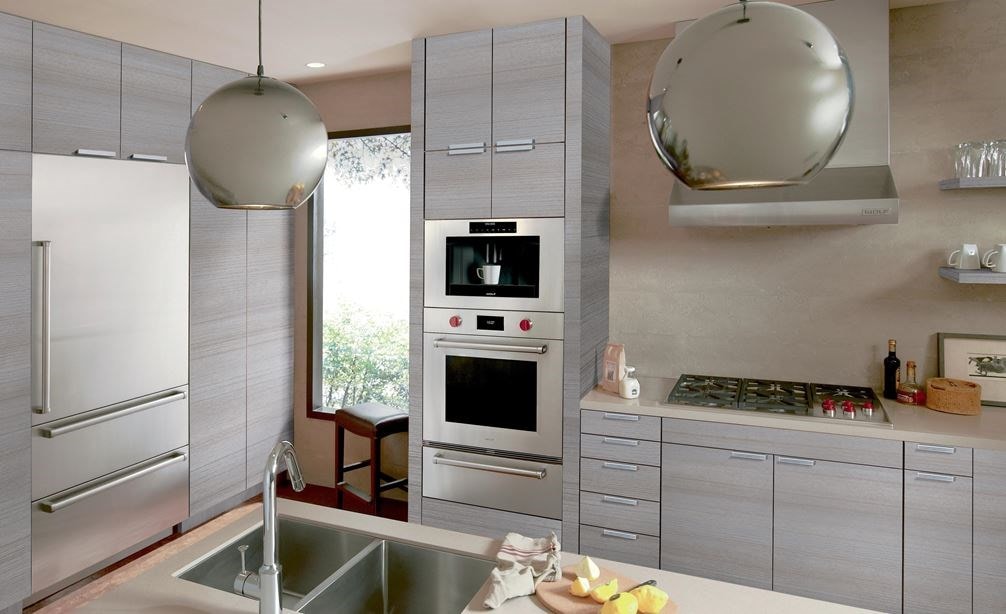 La campana extractora de pared de perfil bajo de 36" Wolf (PW362210) exhibida en un diseño de cocina moderno y limpio que utiliza gabinetes grises con detalles plateados