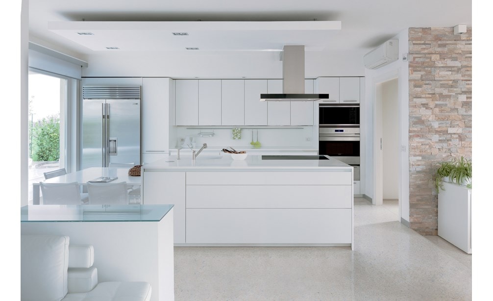 La campana extractora de placa de cocción para isla de 42" Wolf en negro (VI42B) exhibida combinándose a la perfección en un diseño de cocina lineal blanco con gabinetes sin manijas